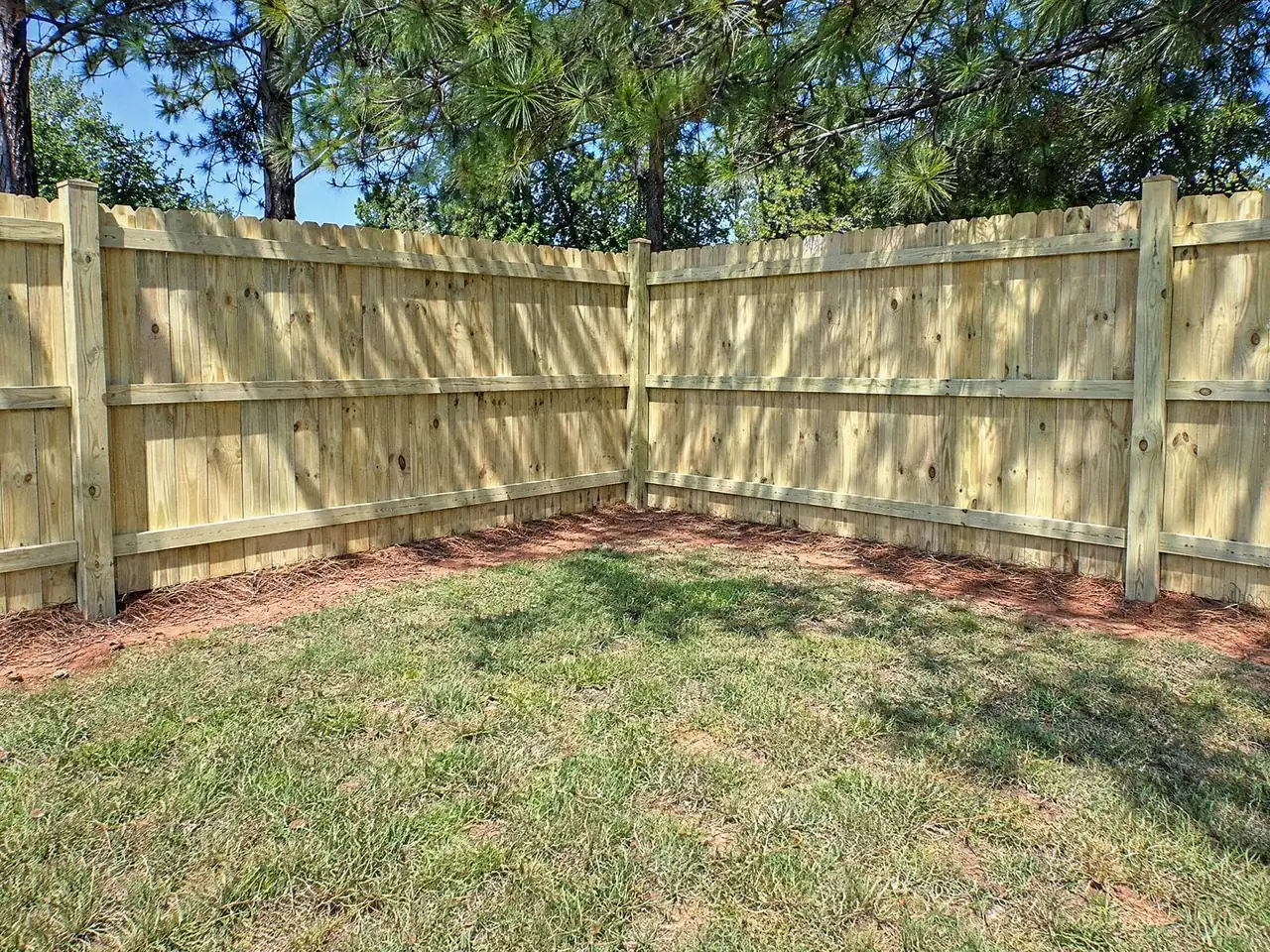 Inside corner of a wood privacy fence seen from the rail side, with posts and rails showing